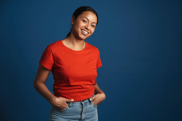 Mladá africká americká žena na sobě tričko s úsměvem na kameru izolované přes modré pozadí - Fotografie, Obrázek