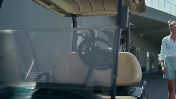 Frau sitzt Golfcart an sonnigem Tag. Profis starten Motor auf Kurs - Filmmaterial, Video