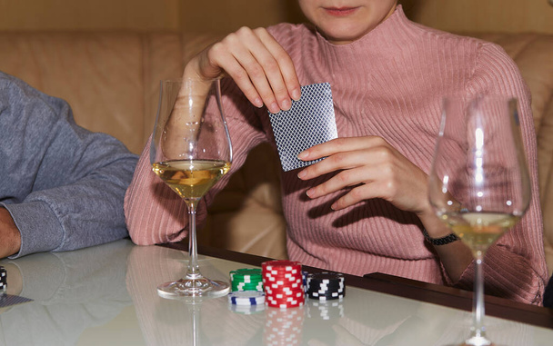 Vrouw houdt speelkaarten in het pokerspel. Kaarten, dobbelstenen en glas champagne. Een openhartig moment. Poker achtergrond lifestyle fotografie. Genieten van het moment, digitale detox met vrienden. - Foto, afbeelding