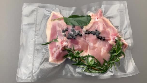 Hühnerschenkel mit Rosmarinsalbei und Gewürzen in vakuumverpackt versiegelt für Sous-Vide-Kochen Slider Track Dolly auf grauem Hintergrund in der Draufsicht - Filmmaterial, Video