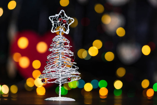 Christmas decoration and ornaments. Christmas composition on blurred lights background.Small silver wire Christmas tree - Photo, Image