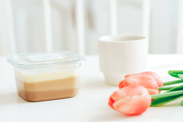 Three types of chocolate in plastic container next to coffee and tulips - Photo, image