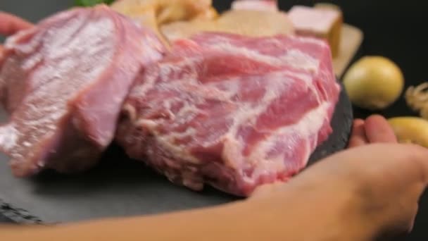 Hands put on a stone plate with pieces of raw meat of veal, pork, chicken. - Filmati, video