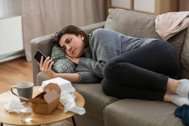 stressed woman with smartphone on sofa at home - Valokuva, kuva
