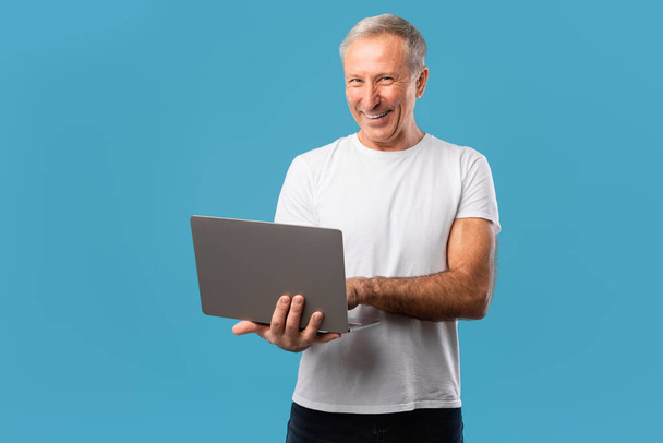 Confident mature man holding and using laptop - Zdjęcie, obraz