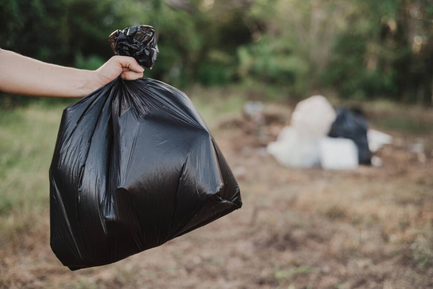 Tenere in mano un sacco della spazzatura pronto per essere portato nel sito di smaltimento dei rifiuti. - Foto, immagini