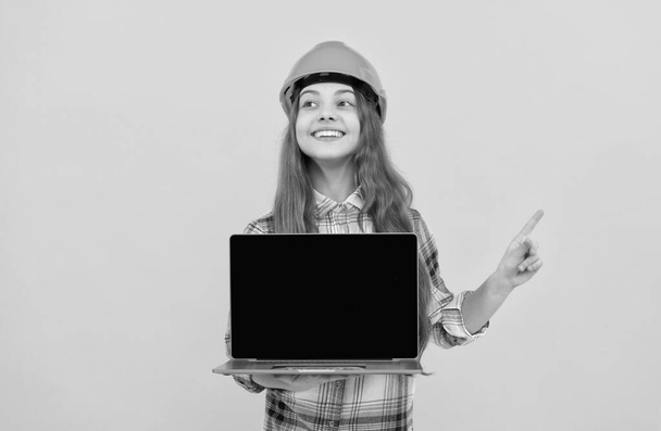 szczęśliwy nastolatek dziewczyna w kasku i w kratkę koszula prezentuje laptop wskazując palec, promocja - Zdjęcie, obraz