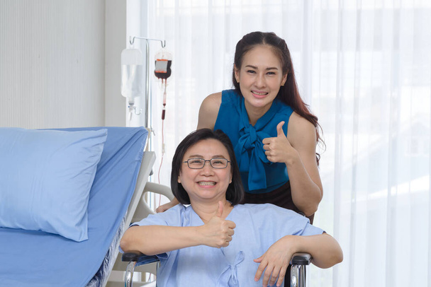 cuidar a la hija adulta cuidando a su madre mayor en silla de ruedas mientras visita al médico - Foto, imagen