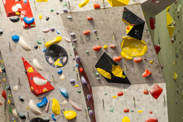 Artificial rock climbing wall with various colored grips - Fotó, kép