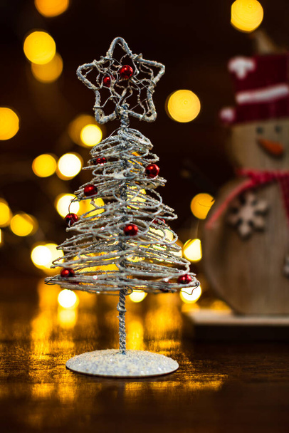 Decoraciones navideñas sobre fondo borroso. Pequeño árbol de Navidad de alambre plateado. Mini árbol de Navidad
. - Foto, imagen