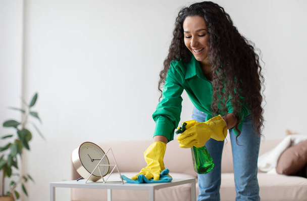 Cheerful Brunette Woman Dusting And Cleaning Desk At Home - Photo, Image