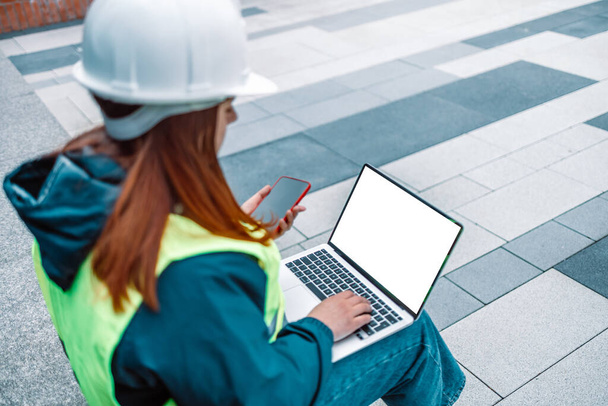Construction woman worker engineer hardhat and safety vest working on laptop with white screen  - Фото, зображення