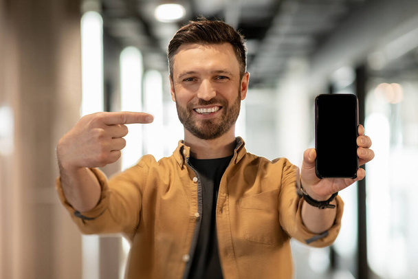Businessman Pointing At Phone Screen Standing In Doorway In Office - Foto, immagini