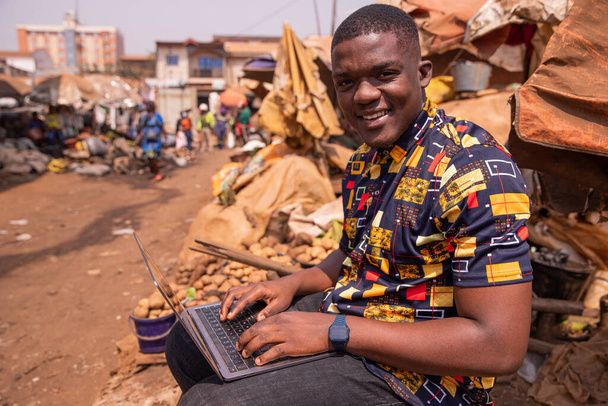 若いアフリカの少年は、市場で彼のコンピュータを使用します,アフリカの若者や技術 - 写真・画像