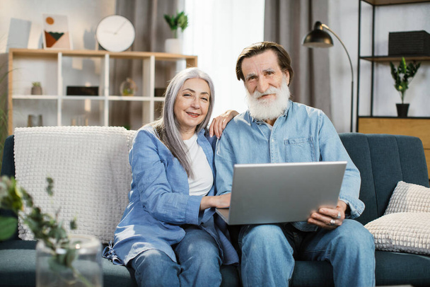 Happy mature couple Using Laptop Watching Movie Together Sitting On Couch At Home. - Fotoğraf, Görsel
