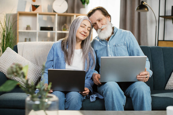 Happy middle aged older retired family couple using computer applications - Foto, Bild