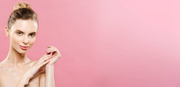 Beauty Spa Concept - Kaukasische vrouw met perfecte gezicht huid portret. Mooie Brunette Spa meisje met lege kopie ruimte. Geïsoleerd op roze studio achtergrond. Stelt een product. - Foto, afbeelding