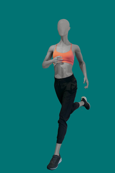 Running image of a female display mannequin wearing sportswear isolated on a blue background - Valokuva, kuva