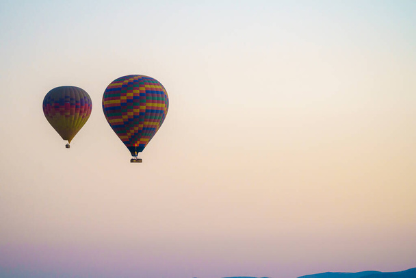 Set of colorful balloons flying over Goreme city in Cappadocia, during sunset on a clear summer day, copy space - Photo, image