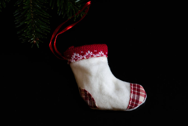 Χριστουγεννιάτικη ιδέα. Χριστουγεννιάτικα στολίδια σε μαύρο φόντο. Μικρή χριστουγεννιάτικη κάλτσα. - Φωτογραφία, εικόνα