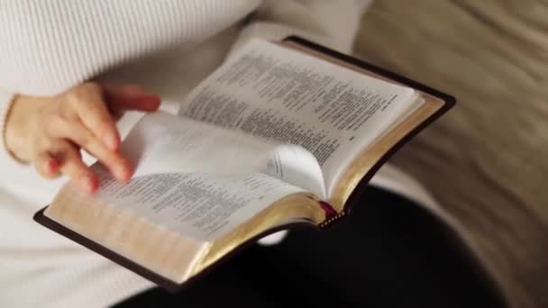 Young Christian girl holds open Holy Bible Book with golden pages at home. Seeking wisdom and knowledge from God Jesus Christ in faith and hope. Biblical concept. A close-up. - Footage, Video