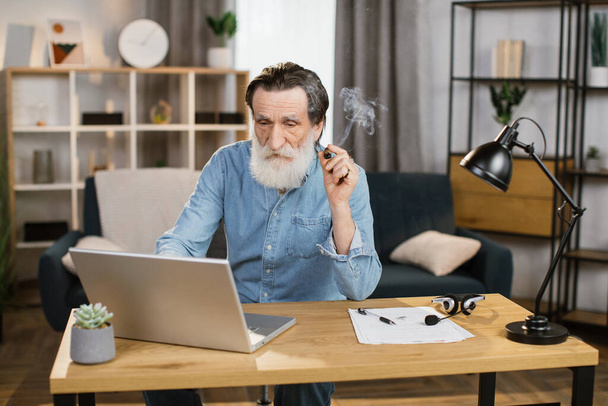 Elegantly looking aged grey-beard mature man chief of big company relaxing at office - Фото, изображение
