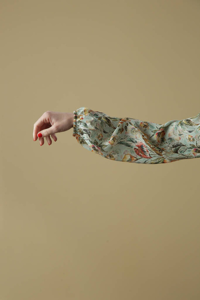 Woman's arm in floral silk blouse, indoor image aganst white wall - Φωτογραφία, εικόνα