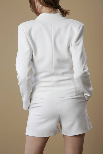 Female model wearing white tailored blazer and short pants. Studio shot. - Foto, Bild