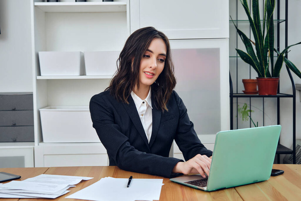 молода бізнес-леді, що працює з ноутбуком і документами в офісі
  - Фото, зображення