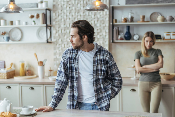 Sad unhappy young european husband with stubble ignores offended wife after scandal in modern kitchen - Photo, Image