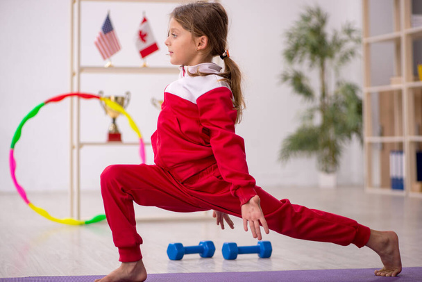 Νεαρό κοριτσάκι κάνει αθλητικές ασκήσεις στο σπίτι - Φωτογραφία, εικόνα