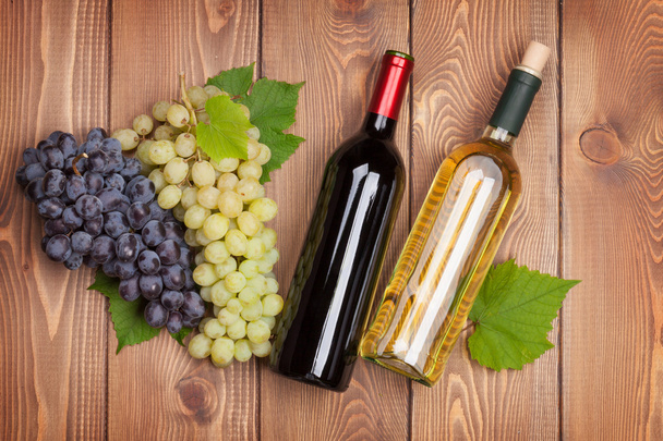 Red and white wine bottles and bunch of grapes - Фото, изображение