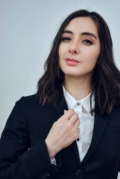 portrait of a beautiful young businesswoman wearing black jacket on a white background - Fotó, kép