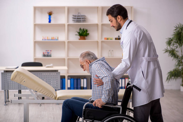 Staruszek na wózku inwalidzkim odwiedza młodego lekarza - Zdjęcie, obraz