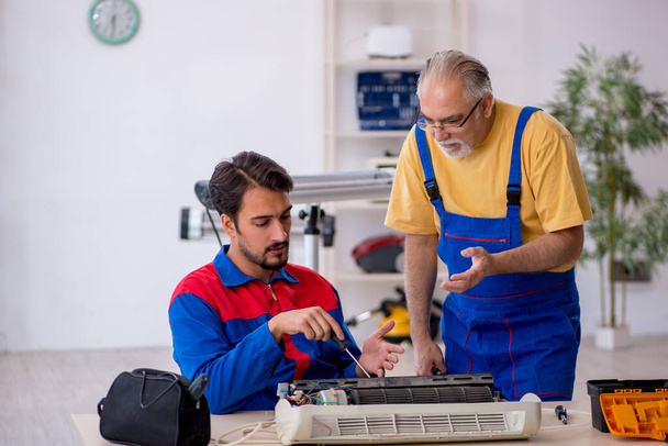 Два чоловіки ремонтують кондиціонер
 - Фото, зображення
