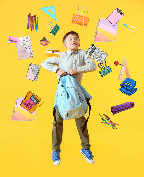 Jumping little schoolboy and different stationery on yellow background - Foto, Imagen