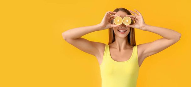 Όμορφη ευτυχισμένη νεαρή γυναίκα με λεμόνια σε πορτοκαλί φόντο με χώρο για κείμενο - Φωτογραφία, εικόνα