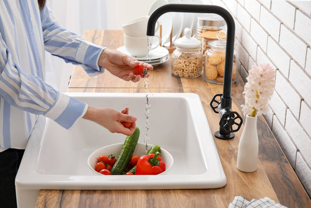 Woman washing fresh vegetables in kitchen sink  - Zdjęcie, obraz