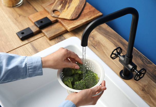 Woman washing fresh broccoli in kitchen sink, closeup - Fotó, kép