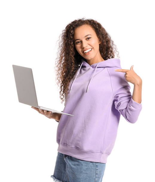 Beautiful young African-American woman in stylish hoodie and with laptop on white background - 写真・画像
