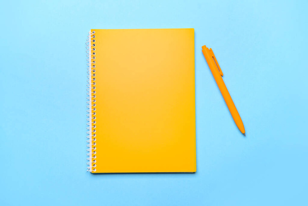 Yellow notebook and pen on color background - Fotoğraf, Görsel
