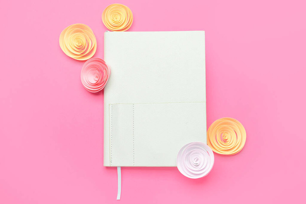 Notebook and paper flowers on pink background - Фото, изображение