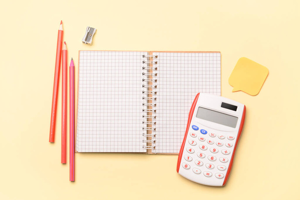 Notebook with colorful pencils and calculator on color background - Foto, imagen
