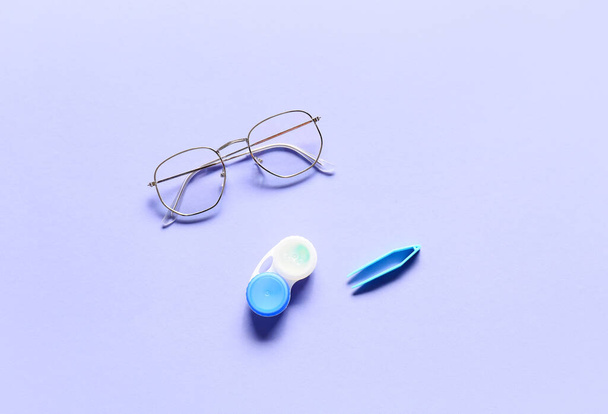 Stylowe okulary i soczewki kontaktowe z pojemnikiem na fioletowym tle - Zdjęcie, obraz