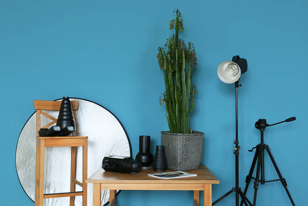 Дерев'яний стіл і стілець з різним обладнанням для фотостудії біля кольорової стіни
 - Фото, зображення