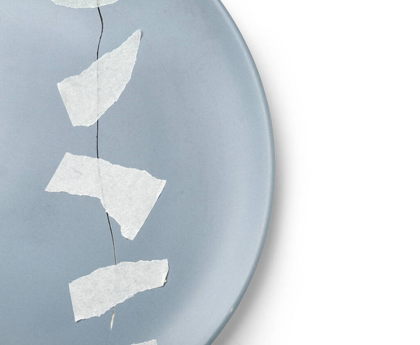 Rozbita płyta ceramiczna z taśmą samoprzylepną na białym tle, zbliżenie - Zdjęcie, obraz