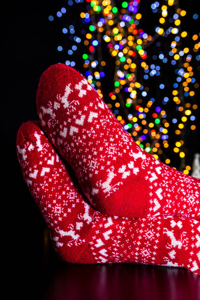 Ноги в зимние рождественские носки на размытых огнях - Фото, изображение