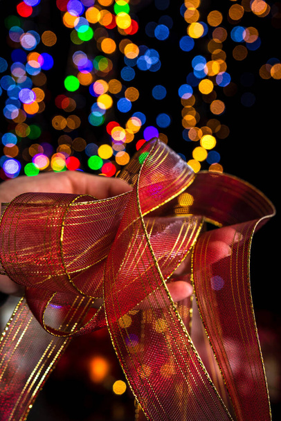 Holding Christmas decoration against bokeh lights background - Foto, afbeelding