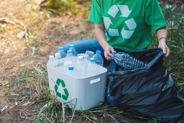 Een vrouw die plastic flessen opraapt in een doos en tas voor recycling concept - Foto, afbeelding