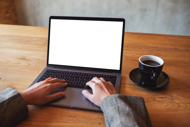 Εικόνα mockup μιας γυναίκας που χρησιμοποιεί και πληκτρολογεί σε φορητό υπολογιστή με λευκή οθόνη γραφείου στο cafe - Φωτογραφία, εικόνα